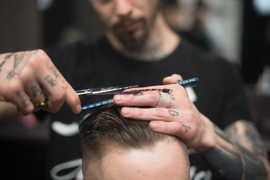 a professional barber cutting the hair of a man sitting on a chair 